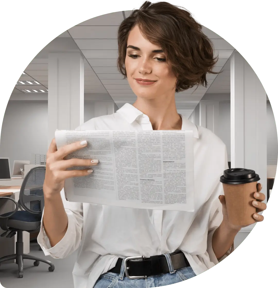 Frau bei der Arbeit in einem Marketingunternehmen liest gerade Nachrichten in einer ausgedruckten Zeitung.